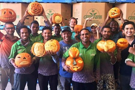 Ceres Farm workers holding carved jack-o-lantern pumpkins in the packing shed