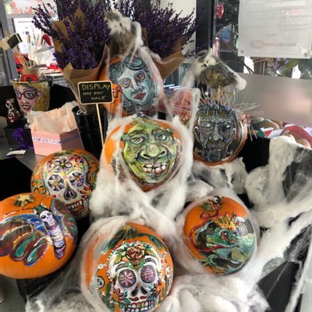Halloween pumpkins painted with faces and skulls in a shop display with cobwebs